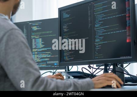 App asiatica di codifica per sviluppatori di ingegneri tempestivi con dati software posizionati di fronte al monitor del computer in ufficio Foto Stock