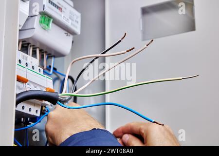 Interventi elettrici sul collegamento del cavo di alimentazione trifase alla rete elettrica domestica in un quadro elettrico. Foto Stock