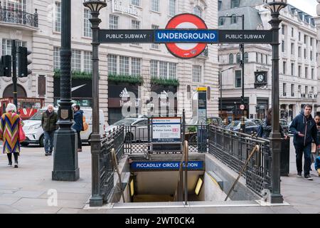 Strade trafficate di Londra a Piccadilly Circus. Ingresso alla metropolitana di Londra con un cartello iconico. Vivaci pedoni e architettura storica. Foto Stock