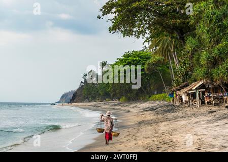 Commerciante presso la spiaggia di Mangsit a Sengiggi, venditore, uomo, spiaggia di palme, viaggi, turismo, mare, spiaggia, acqua, palma, oceano, isola, costa, tropicale, tropicale Foto Stock