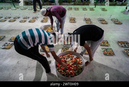 I volontari distribuiscono e organizzano file di pasto 'iftar' per i devoti per rompere il loro digiuno, durante il mese sacro del Ramadan, a Burha Jame Masjid, ON Foto Stock