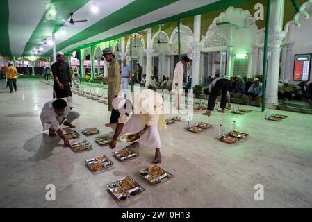 I volontari distribuiscono e organizzano file di pasto 'iftar' per i devoti per rompere il loro digiuno, durante il mese sacro del Ramadan, a Burha Jame Masjid, ON Foto Stock