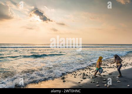 Donna musulmana al sole della sera sulla spiaggia di Mangsit a Sengiggi, Islam, religione, velo, viaggi, turismo, mare, spiaggia, acqua, rispetto, drammatico Foto Stock