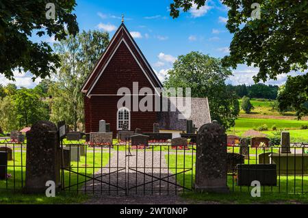 Un cimitero con lapidi e tombe è visto in primo piano, mentre una chiesa si erge alto sullo sfondo. La chiesa torreggia sopra il groun sepolcrale Foto Stock