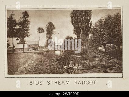 Radcot. Sist. Henry W. Taunt, fotografo (britannico, 1842 - 1922) intorno al 1886 una delle tre fotografie che illustrano una mappa stampata di Kelmscott, Thrupp e l'area circostante lungo il Tamigi. La fotografia mostra una vista del ponte ad arco in pietra sul fiume a Radcot. Un uomo siede in kayak sull'acqua in primo piano, mentre un secondo uomo si siede sulla riva, entrambi con la testa rivolta verso la telecamera. Uno stretto sentiero sterrato corre parallelo all'acqua e conduce verso diversi edifici sulla riva del fiume accanto al ponte. (Recto, montaggio) centro inferiore, sotto l'immagine, prin Foto Stock