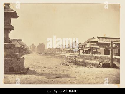 Scena del villaggio. Charles Parker, fotografo (britannico, attivo negli anni '1860) circa 1864 Vista di un villaggio o di una piccola città con un'ampia strada che la attraversa. La strada è fiancheggiata su entrambi i lati da abitazioni a due piani, per lo più con tetti di paglia. Nell'area sinistra dell'immagine è visibile anche una grande struttura in pietra a forma di lanterna giapponese, sollevata su un piedistallo. Foto Stock