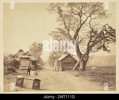 Tokaido. Felice Beato, fotografo (inglese, nato in Italia, 1832 - 1909) Barone Raimund von Stillfried, stampatore (austriaco, 1839 - 1911) 1860 Vista di un uomo in piedi sulla strada Tokaido. Guarda la telecamera e tiene entrambe le mani con il palmo in alto. Due scatole rettangolari identiche attaccate alle estremità di un palo per il trasporto si trovano sulla strada in primo piano, ciascuna dipinta con un logo di tre triangoli disposti a piramide circondati da un cerchio. Una manciata di edifici con tetto in paglia fiancheggiano entrambi i lati della strada sterrata. (Recto, stampa) in basso a sinistra, scritto a mano in negativo: "TOKAIDO". Foto Stock