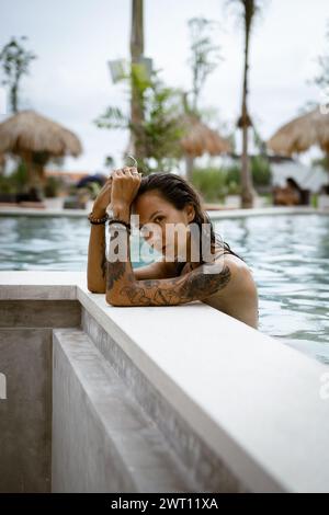 Giovane donna tatuata che si rilassa in piscina. Foto Stock