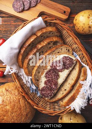 Affettare il salame piccante sulla fetta di pane e spalmare il burro Foto Stock