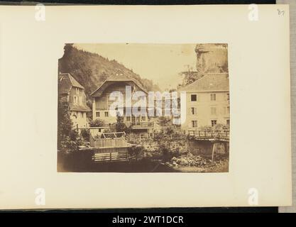 Città di montagna. Sir John Joscelyn Coghill, fotografo (irlandese, 1826 - 1905) intorno agli anni '1850 Un gruppo di grandi edifici e un hotel lungo un fiume. Le montagne sono visibili sullo sfondo. C'è una piccola casa con un tetto curvo e appuntito al centro dell'immagine. Un giovane può essere visto in piedi sul balcone della piccola casa. (Recto, montaggio) in alto a destra, matita: "87"; Foto Stock