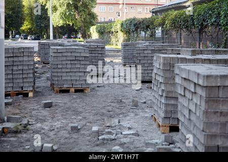 Cantiere di lavori di riparazione stradale per pavimentazione e ripavimentazione di piastrelle marciapiede. Lastre di pietra su pallet in una strada cittadina Foto Stock