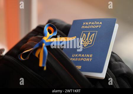 Passaporto biometrico ucraino su zaino turistico nero con nastro ucraino da vicino Foto Stock