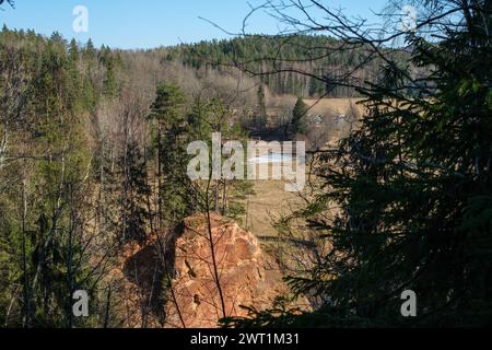 Esplora le meraviglie di Amatas Dabas Taka, dove il viaggio del fiume si riflette sulla maestosa presenza di scogliere Foto Stock