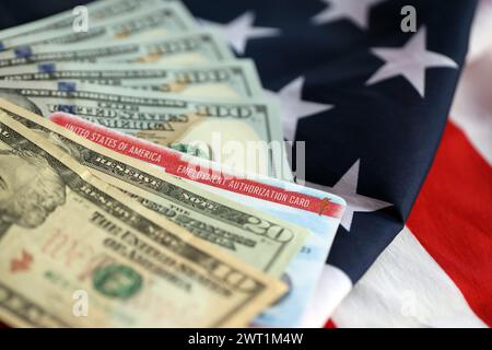 Carta di autorizzazione all'impiego permesso di lavoro degli Stati Uniti d'America e bollette in dollari sulla bandiera americana piegata primo piano Foto Stock