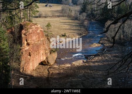 Scopri le meraviglie di Amatas Dabas Taka, dove la serenità del fiume è impreziosita dal maestoso sfondo delle scogliere. Foto Stock