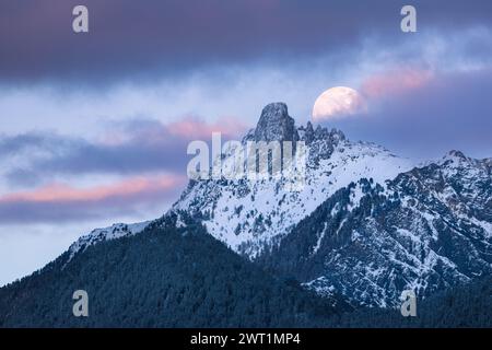Una splendida vista della luna piena parzialmente coperta sul monte Pierre Avoi al tramonto Foto Stock