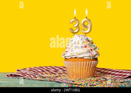 Torta di compleanno con candela numero 39 - foto su sfondo giallo. Foto Stock