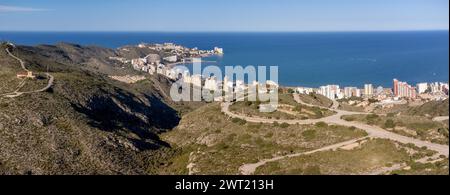 Una fotografia paesaggistica che cattura la costa di Cullera con la catena montuosa di Cullera in primo piano. Sullo sfondo l'appartamento estivo Foto Stock