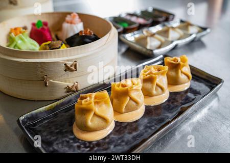 Una squisita selezione di dim sum al vapore su un piatto elegante, che mostra arte culinaria e sapore. Foto Stock