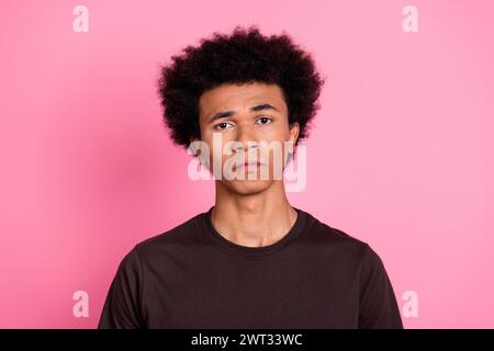 Foto di un giovane studente triste infelice capelli ricci in maglietta marrone insoddisfatto depresso isolato su sfondo di colore rosa Foto Stock