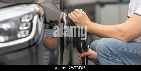 Dettagli professionali di un'auto in studio auto, mani con lucidatrice orbitale, sgrassante, concetto di cura del veicolo Foto Stock