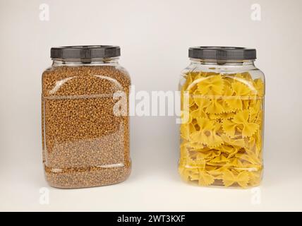 Grano saraceno e pasta in un contenitore di plastica. Pasta con archi. Vasetti con grano saraceno e pasta. Il concetto di conservazione dei cereali per la cottura. Foto Stock