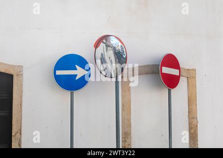 svolta a destra e fermati con uno specchio circolare accanto a un muro bianco in una strada Foto Stock