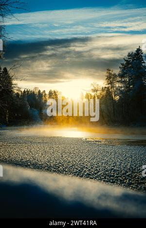 Un sole che tramonta sul lago ghiacciato con acqua nebbiosa Foto Stock