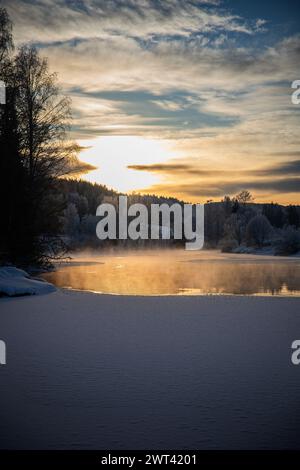 Un tramonto sull'acqua con bassa nebbia e sole che tramonta Foto Stock