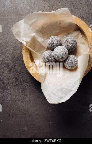 Caramelle fatte in casa in fiocchi di cocco su sfondo scuro. Foto Stock