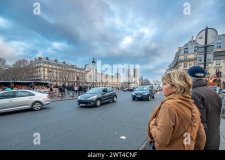 Una coppia in piedi in strada con Notre Dame sullo sfondo in Quai Saint Michel Street a Parigi, Francia. Foto Stock