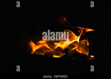 Fiamme arancioni su sfondo nero. Fiamme drammatiche sfarfallio contro l'oscurità. Incendio ed elemento termico, pericolo, intensità, contrasto. Fuori dal foc Foto Stock