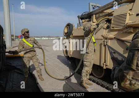 PFC. Kamden Briggs (a sinistra) e Sgt. Cesar Miranda, operatori del trasporto a motore con il 18th Combat Sustainment Support Battalion, 16th Sustainment Brigade, riforniscono un veicolo da combattimento m2 Bradley Infantry dal 3rd Armored Brigade Combat Team, 4th Infantry Division presso il porto di Alexandroupolis, Grecia, 11 marzo 2024. Il personale degli Stati Uniti e della Grecia ha spostato circa 3.000 equipaggiamenti per il dispiegamento a rotazione del 3° ABCT in Europa per scoraggiare l'aggressione e assicurare gli alleati della NATO. Questa missione ha fatto la storia del sostentamento, facilitando l'accoglienza, la messa in scena e il movimento successivo della prima “h” Foto Stock