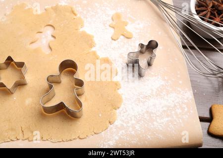 Preparare biscotti di Natale. Impasto crudo, frusta e taglierine di diverse forme su un tavolo di legno Foto Stock