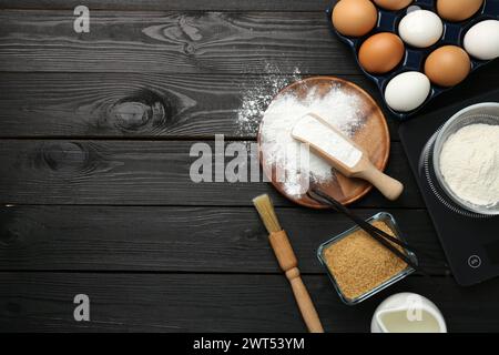 Composizione piatta con lievito in polvere e prodotti su un tavolo di legno nero. Spazio per il testo Foto Stock