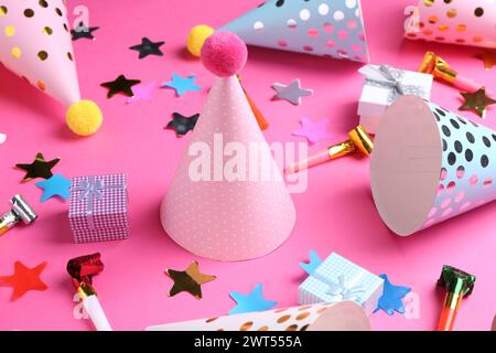 Cappelli da festa e altri elementi decorativi luminosi su sfondo rosa Foto Stock