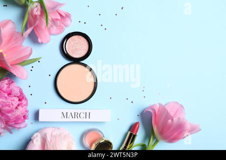 Giornata internazionale della donna. 8 marzo in polvere, prodotti per il trucco e bellissimi fiori su sfondo azzurro, piatto. Spazio per il testo Foto Stock