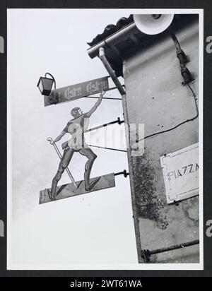 Lazio Viterbo Montefiascone vedute generali. Hutzel, Max 1960-1990 Vista di un cartello della locanda in Piazza Roma che recita 'Est! Est!! Est!!!,' (vedi TCI, Lazio pp. 335-336 per il significato). Vista su un portale, restaurato nel 1744, che conduce alla parte più antica di Montefiascone. Il fotografo e studioso tedesco Max Hutzel (1911-1988) fotografò in Italia dai primi anni '1960 fino alla sua morte. Il risultato di questo progetto, citato da Hutzel come foto Arte minore, è un'accurata documentazione dello sviluppo storico dell'arte in Italia fino al XVIII secolo, che comprende oggetti degli Etruschi e dei Romani Foto Stock