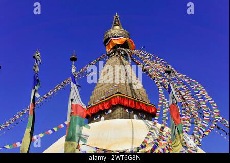 Stupa Bodnath o Boudhanath o Boudha, patrimonio dell'umanità dell'UNESCO, la cima di uno stupa buddista con bandiere di preghiera ondeggianti contro un cielo blu, Kathmandu Foto Stock