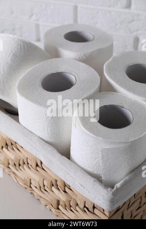 Rotoli di carta igienica nel cestello in vimini su tavolo bianco Foto Stock