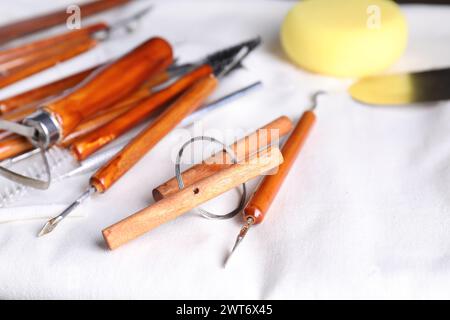 Set di diversi utensili per la lavorazione dell'argilla su tavolo in legno, primo piano Foto Stock