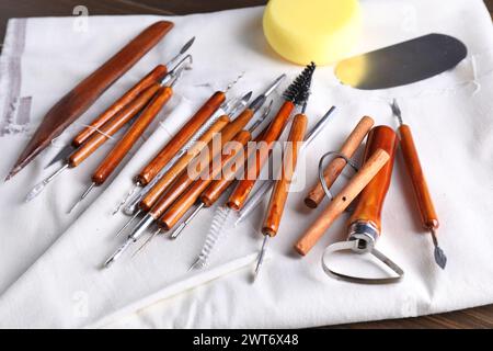 Set di diversi utensili per la lavorazione dell'argilla su tavolo in legno, primo piano Foto Stock