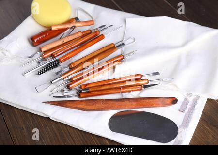 Set di diversi utensili per la lavorazione dell'argilla su tavolo in legno, primo piano Foto Stock