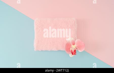 Composizione creativa realizzata con fresco fiore naturale di orchidea e spazio per copiare la pelliccia sintetica rosa pastello su sfondo geometrico astratto rosa pastello e blu. Foto Stock