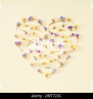 Forma del cuore fatta di fiori secchi colorati su sfondo color crema pastello. Romantico biglietto d'auguri floreale. Concetto d'amore minimalista e semplicità. Decorazioni naturali. Foto Stock