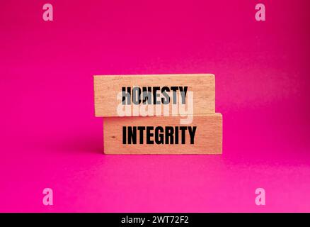 Parole di onestà e integrità scritte su blocchi di legno con sfondo rosa. Simbolo concettuale. Copia spazio. Foto Stock