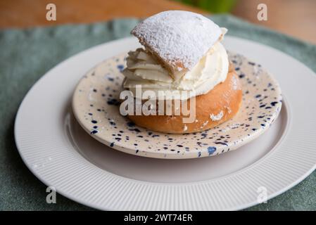 Tipica semla svedese con crema dolce su tessuto blu. Foto Stock