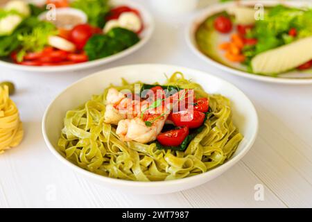 Spaghetti con spinaci, pomodori e gamberi. Specialità di pesce. Produzione domestica. Copia spazio Foto Stock