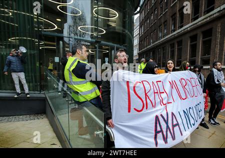 I manifestanti tengono uno striscione che dice che gli omicidi di ëIsrael, AXA Insuresí e cantano la loro disapprovazione fuori dagli uffici di AXAís durante la manifestazione. I manifestanti del fronte Giovanile per la Palestina (YFFP) e i loro sostenitori chiedono un boicottaggio dell'AXA, poiché affermano di investire oltre un miliardo di dollari in insediamenti illegali su quella che era una volta la terra palestinese e di tenere milioni in investimenti in tre banche israeliane. Affermano con questo sostegno finanziario che compagnie come AXA sono complici dei crimini di Israele contro i palestinesi a Gaza e altrove. Foto Stock