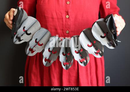 Preparativi per Halloween. Giovane donna con garland festoso su sfondo nero con spazio per le copie. Foto ravvicinata delle decorazioni di Halloween. Foto Stock